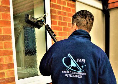 EVANS CLEANING SERVICES CLEANING A WINDOW WITH BRUSH